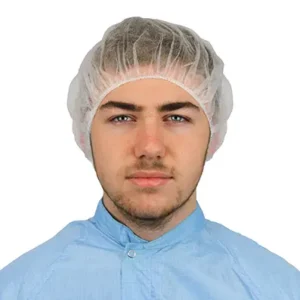 Cleanroom operative wearing a white pleated flat packed bouffant cap and blue permanent coverall